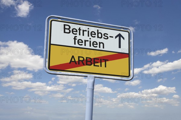 (photomontage) : Town exit sign with the inscription BETRIEBSFERIEN / ARBEIT against a blue sky