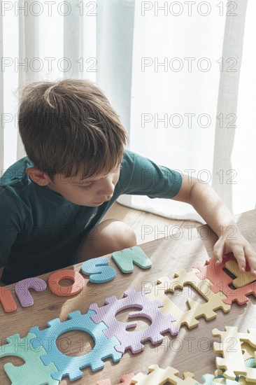 Child assembling colorful puzzle pieces on a wooden table in a bright indoor space during the day
