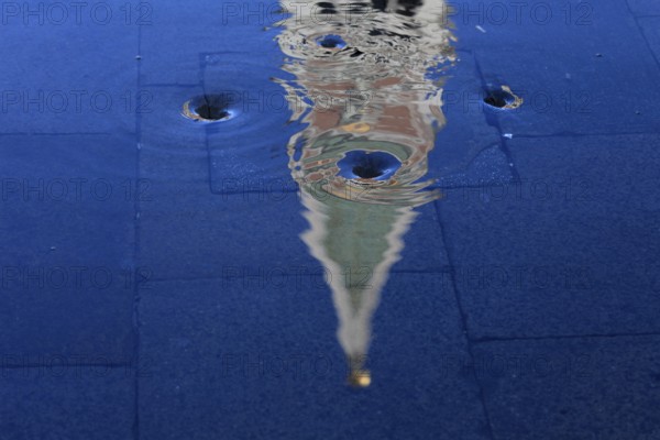 Reflection of the Campanile with water vortex of the flowing flood water, Acqua alta, Venice,
