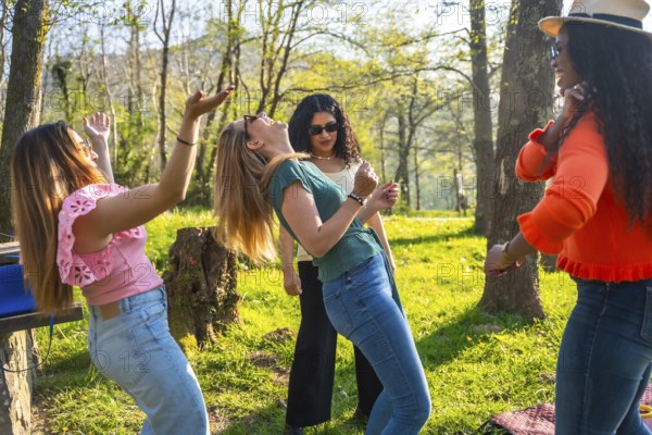 Four friends enjoying a sunny day in the park, dancing and listening to music from a portable