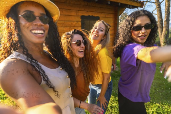 Four multi ethnic female friends are laughing and taking a selfie on a sunny day, enjoying their