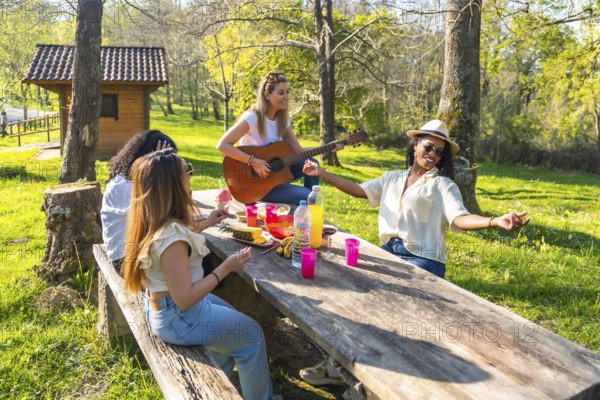 Four young women enjoying a sunny day at the park, playing music, eating fruit, and having fun