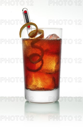 Campari cocktail in a long drink glass on ice with orange zest as garnish against a white