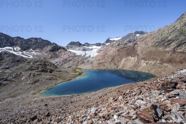 Mountaineer on hiking trail, view of blue glacial lake in rocky mountain landscape, behind