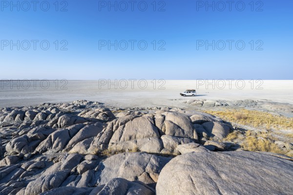 Round rocks of Kubu Island with view over the salt pan, off-road vehicle on the salt pan, Kubu