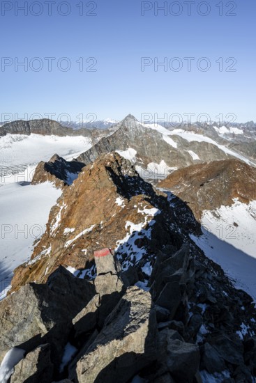 Narrow rocky ridge on the Wilder Freiger summit, picturesque high mountain landscape with snow,