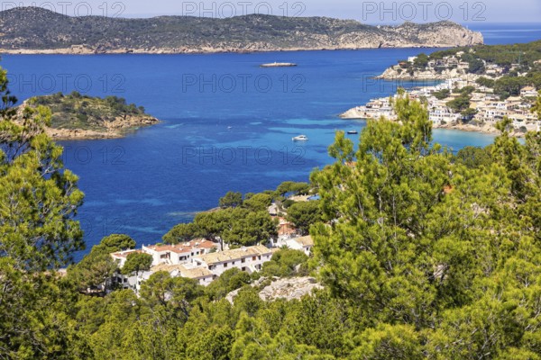 View at a coast village with white houses by a sea bay and a scenic sea view and lush green trees a
