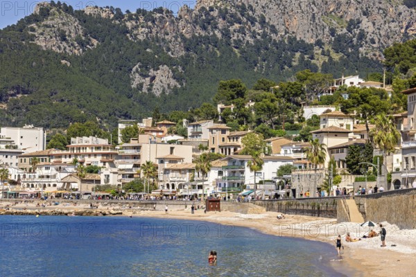 People sunbathing and bathing on the seashore at a idyllic coast village with houses at the
