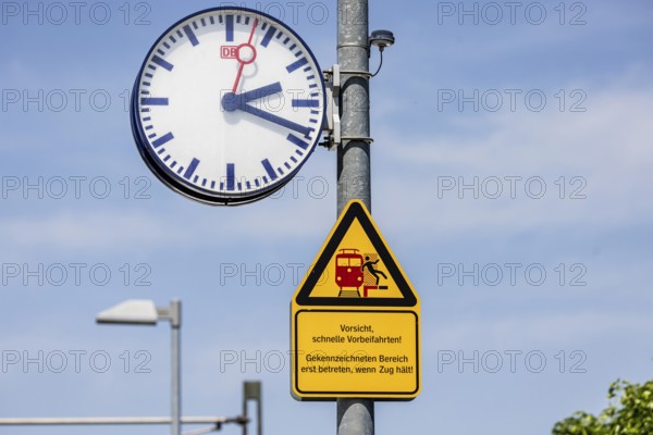 Platform with signs, station clock and warning sign Caution, fast passing. Karlsruhe,