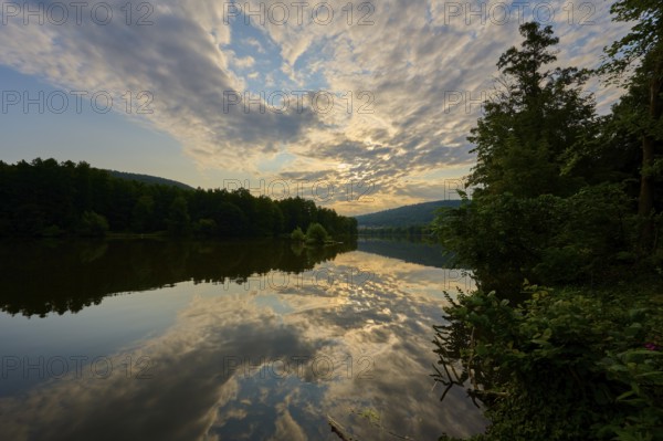 A quiet river with dramatic sky and clouds in the golden light of sunrise, summer, Grünenwört,