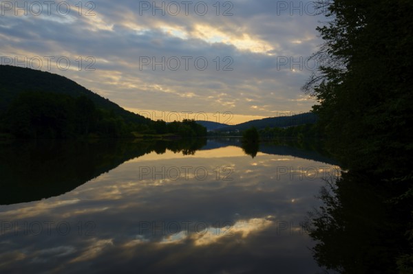 A calm river at dusk with dramatic clouds reflected in the water, summer, Grünenwört, Wertheim,