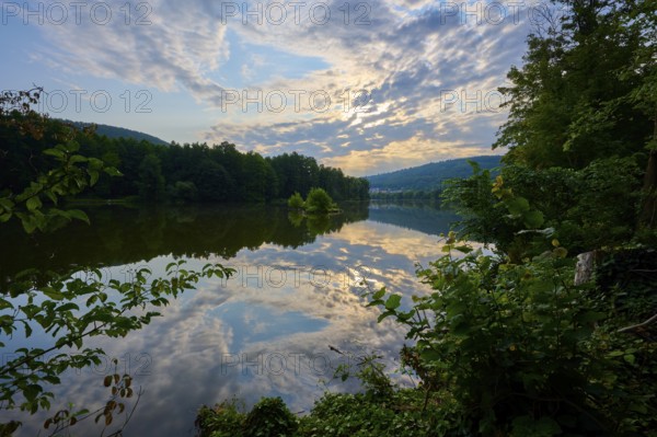 A dramatic sky reflected in a quiet river, surrounded by lush trees, summer, Grünenwört, Wertheim,