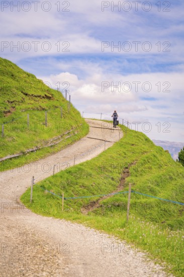 Motorcyclist on a winding gravel road in a hilly landscape, Alpe di Siusi, Dolomites, South Tyrol,