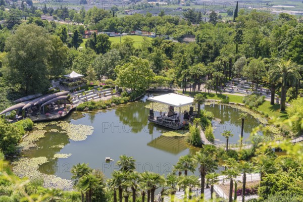 A pond with a pavilion in the middle of a green park, surrounded by landscape, Botanical Garden,
