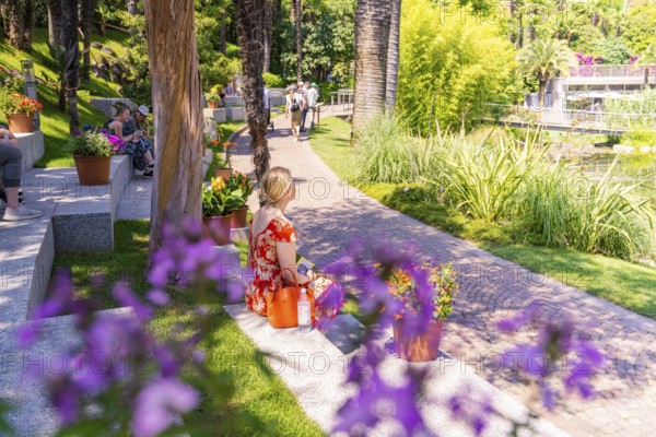 People relaxing in a sunny park with flowers and green grass, Botanical Garden, The Gardens of