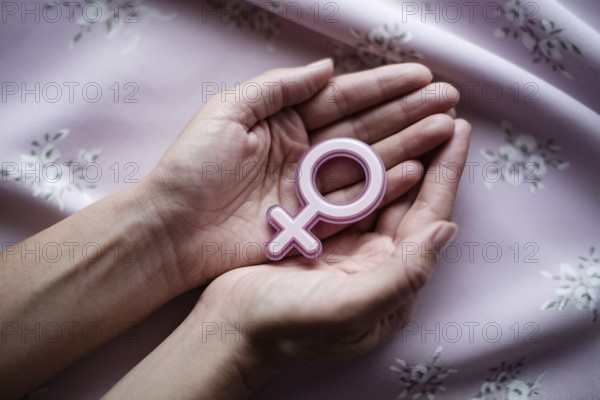 Woman's hands cradling glossy female gender symbol. A visual tribute to strength, femininity, and