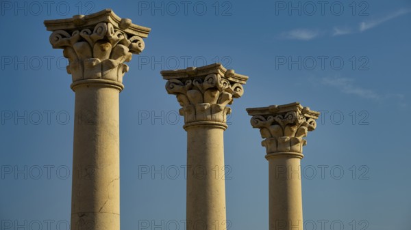 Three ornate ancient columns rising against the blue sky, Temple of Apollo, Corinthian Columns,