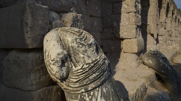 Broken ancient statue on a ruined stone wall illuminated by sunlight, ancient statue of the gods,