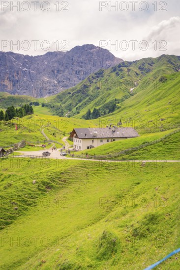 Large building nestled in a green mountain landscape under a cloudy sky, Alpe di Siusi, Dolomites,
