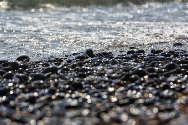 Shiny pebbles on the beach illuminated by the sun, sparkling lights, bokehballs, Insel Düne,