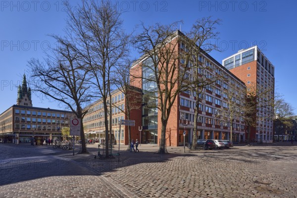 Stadthaus 1, city centre, brick building, bare wintry trees, cobblestone street, blue cloudless