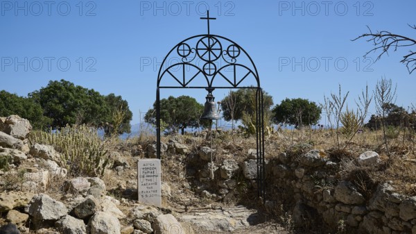 Bell tower with cross in a ruin with trees and clear sky in the background, Church of Agia