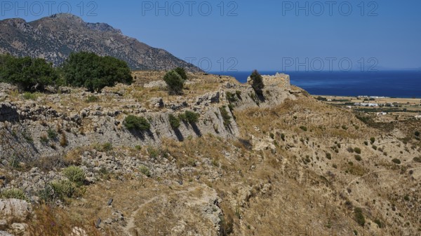 Rocky ruins on a coastal landscape with sea and sunny sky, Kardamina, Antimacheia, Medieval
