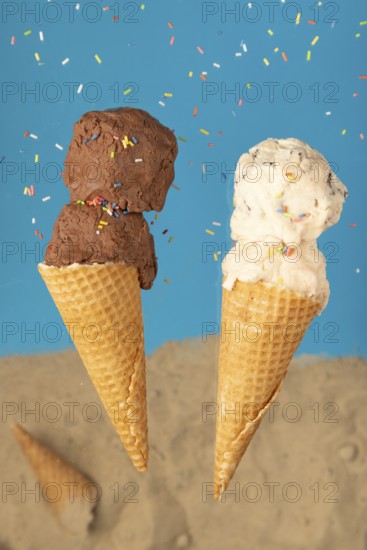 Two ice cream cones, one with chocolate ice cream and one with cream ice cream, against a blue