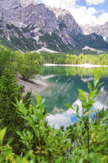 A tranquil mountain lake, surrounded by trees and mountains, reflects the sky and the surrounding