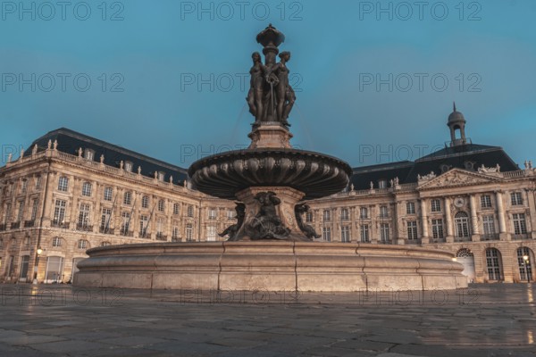 The fountain of the three graces graces place de la bourse in bordeaux, france, illuminated by the