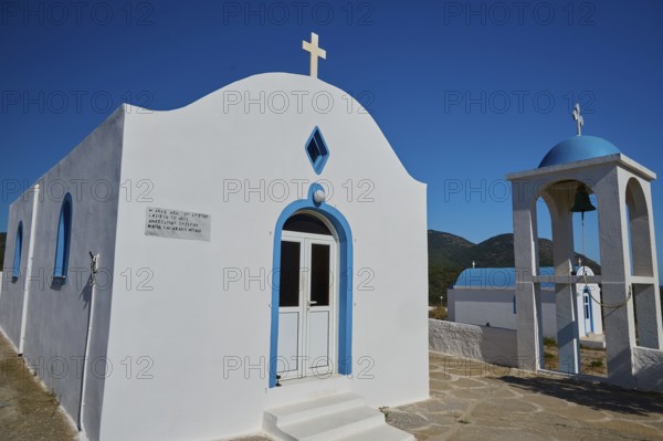 Chapel of Agios Charalambos, White chapel with blue detail and a bell tower under a clear sky,