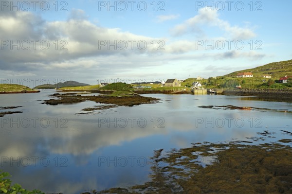 Calm lake in idyllic surroundings with clouds and houses in the background, evening mood, Isle of
