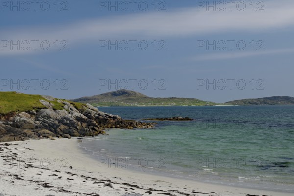 Quiet beach with white sand and rocks, surrounded by blue sea and clear sky, Eriksay, South Uist,