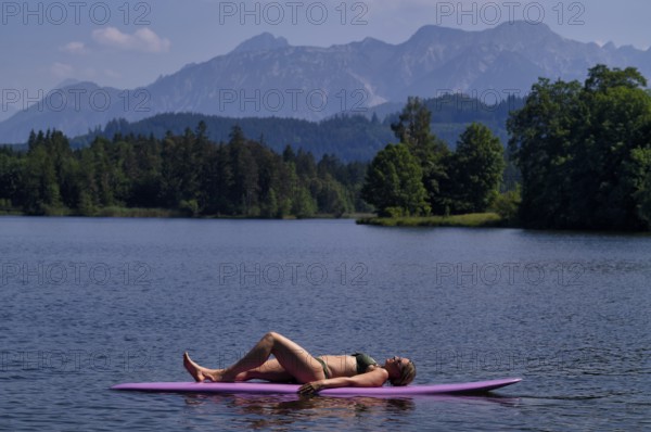 Woman, blonde, in bikini, lying on board, surfboard, surfboard, purple, relaxed, bathing lake,