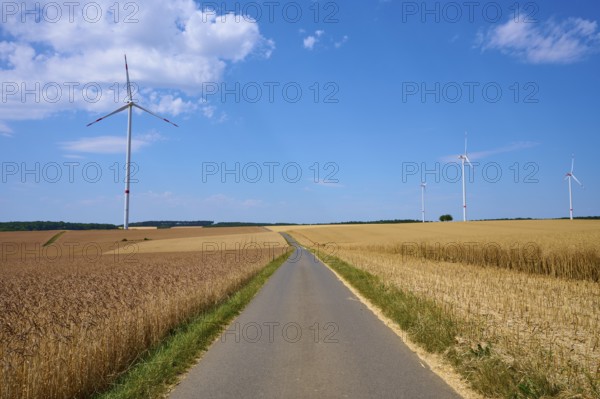 Several wind turbines above golden cornfields under a clear summer sky, summer, Retzstadt, Main