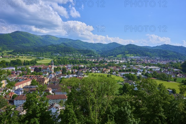 View of a district town surrounded by green hills under a cloudy blue sky, Waldkirch, Breisgau,