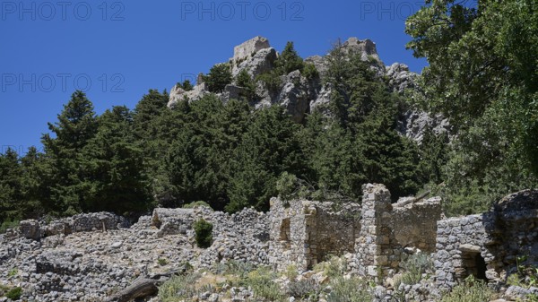 Ancient ruins in front of a wooded hill with clear blue sky in the background, Abandoned Village,