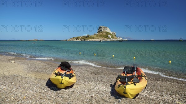 Two kayaks on the beach with a view of a small island in the blue sea, Agios Stefanos Beach, Agios