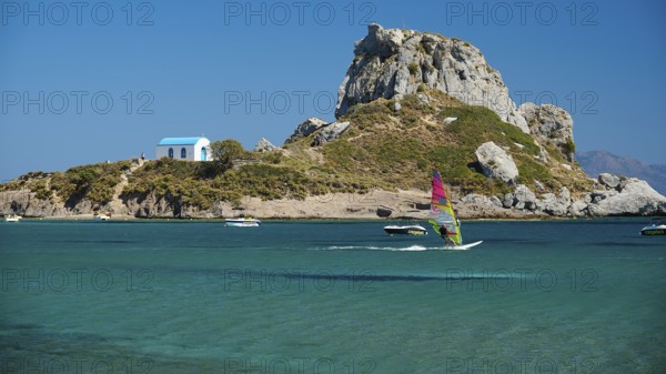 Island with windsurfer and chapel, surrounded by turquoise water, Agios Stefanos Beach, Agios