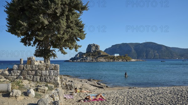 Summer beach view with view of a small island and chapel, Agios Stefanos Beach, Agios Stefanos