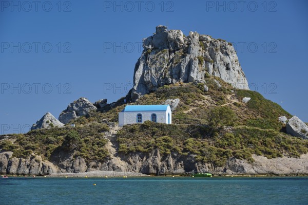 Top of a rocky island with chapel and blue roof, Agios Stefanos Beach, Agios Stefanos Basilica,