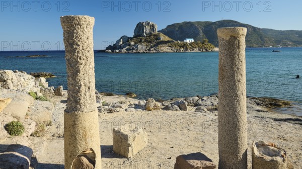 Ancient columns on the coast with a view of an island and the blue sea, Agios Stefanos Beach, Agios