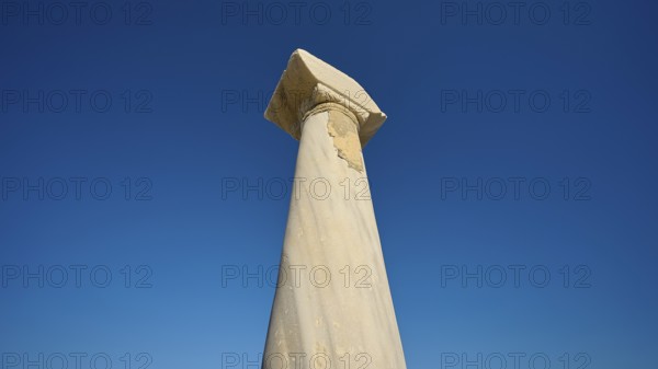 Ancient column imposing against deep blue sky, Agios Stefanos Beach, Agios Stefanos Basilica,