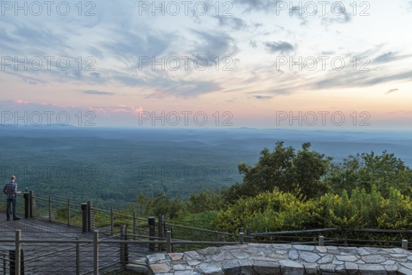 Man looking out over the valley at sunset from the Vista Cliffside Restaurant in Cheaha State Park