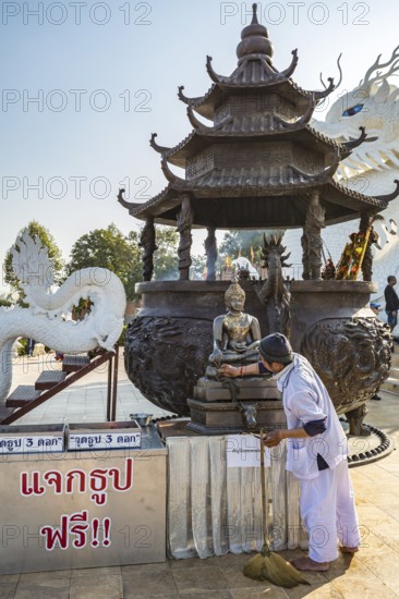 Worker cleaning Buddhist statue in fron of the Guan Yin (Goddess of Mercy) statue at Wat Huay Pla