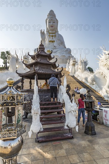 Visitors make a wai phra offering to Buddah in front of the Guan Yin (Goddess of Mercy) statue at