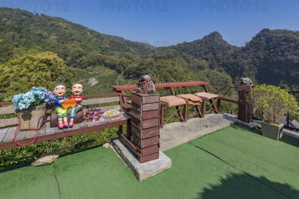 Ceramic statue of Thai couple holding a heart on a bench at the Doi Phamee coffee shop and