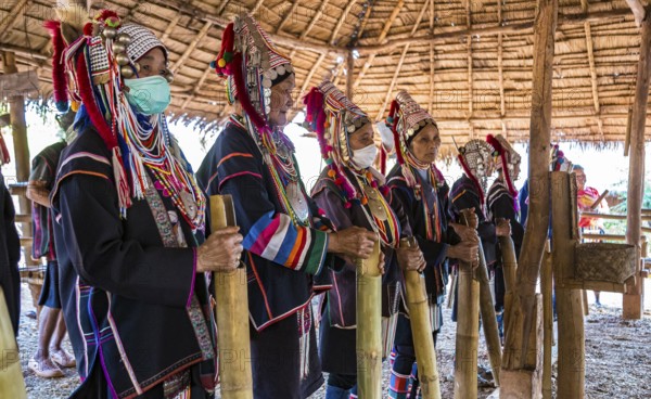 Elderly traditionally dressed people perform a musical chant for a fee in the Akha tribe area of