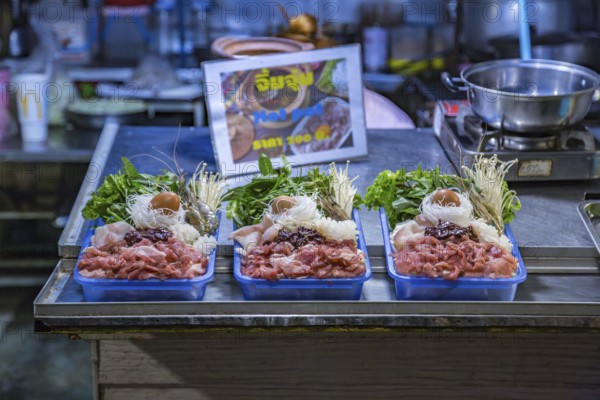 Thai street vendor offers hot pot meal package for customer to cook on a hot pot at their table at