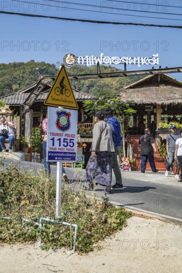Sign encouraging tourists to call police if needed while visiting Pha Mi Village in Mae Sai